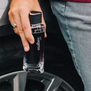 Homem escorado em carro de luxo segurando um frasco do perfume Malbec Icon de O Boticário.