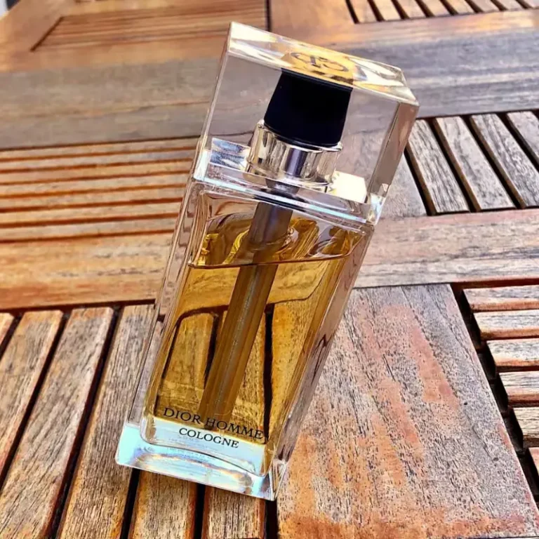 Frasco do perfume Dior Homme Cologne equilibrado em uma mesa de madeira.