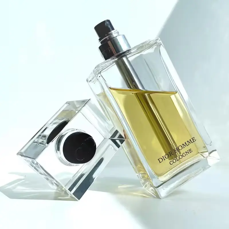 Frasco do perfume Dior Homme Cologne equilibrado na própria tampa, refletindo controle e poder.