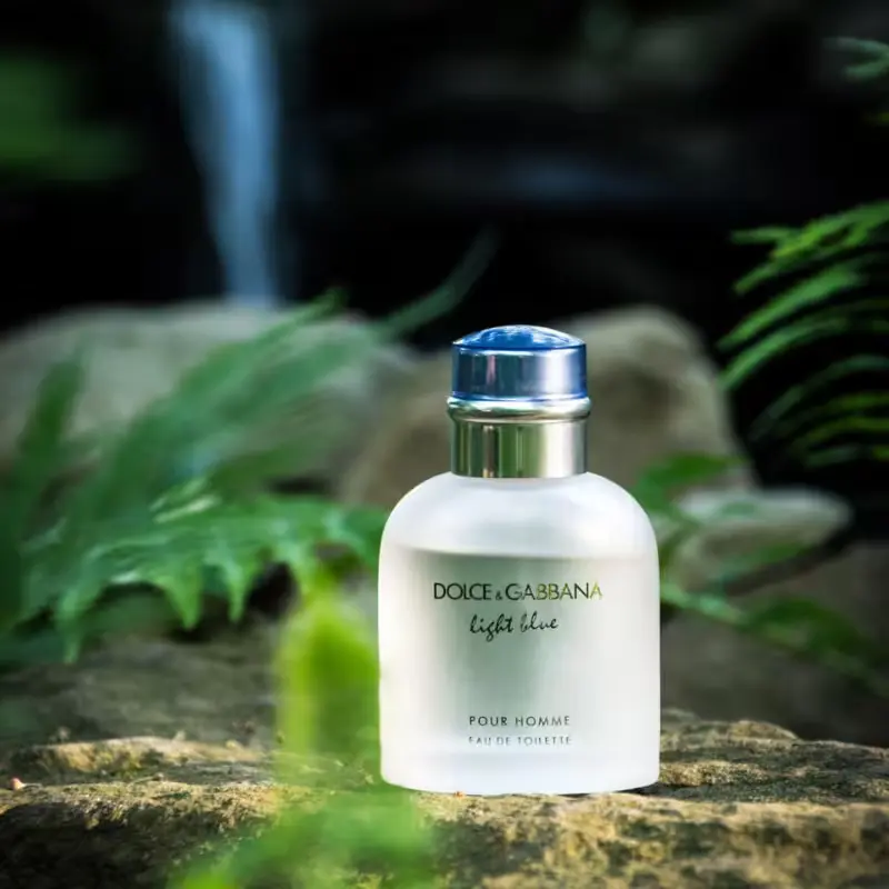 Frasco do Light Blue pour Homme posicionado em um ambiente natural, sugerindo elegância e presença marcante.